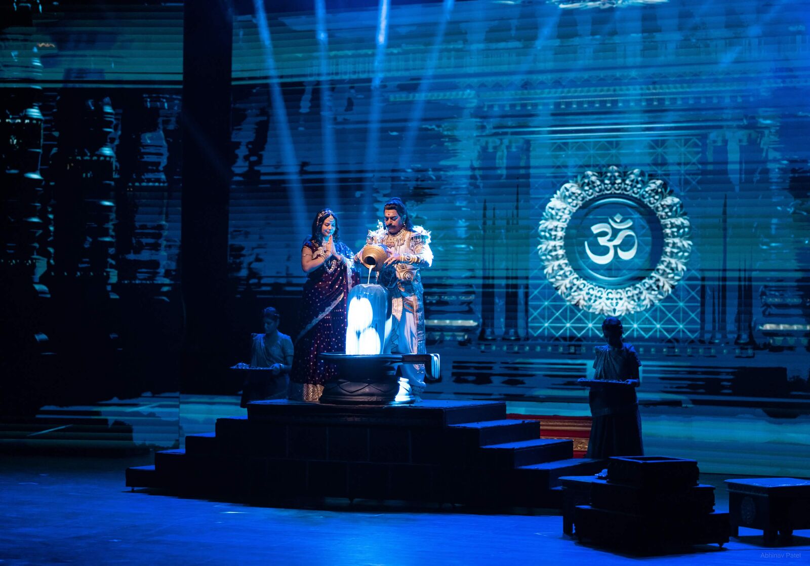 Performers pouring water during a blue-lit stage ritual