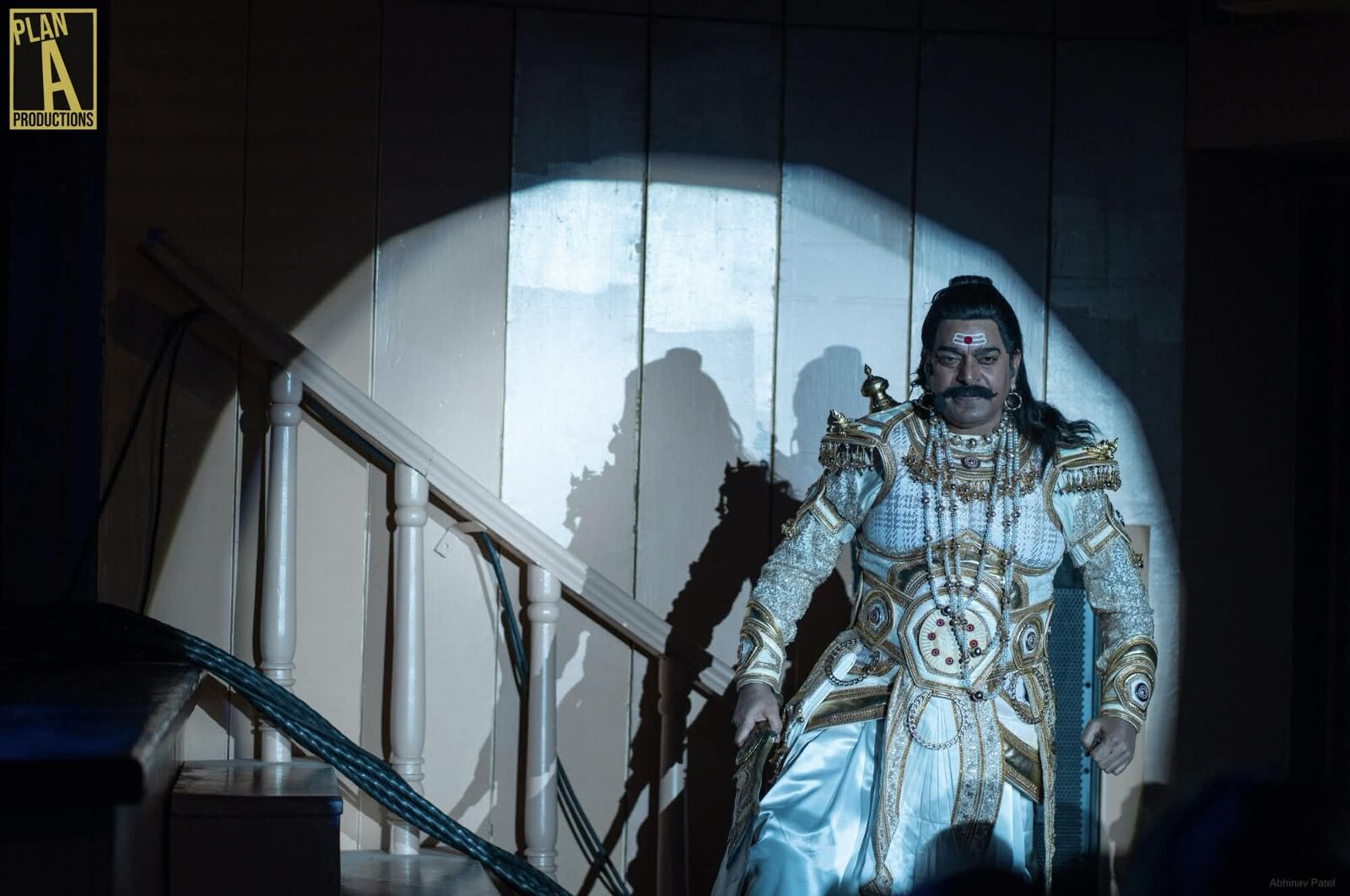 Silver-costumed performer entering under a spotlight